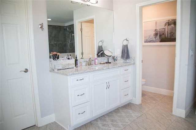 full bathroom with vanity, a tile shower, toilet, and baseboards