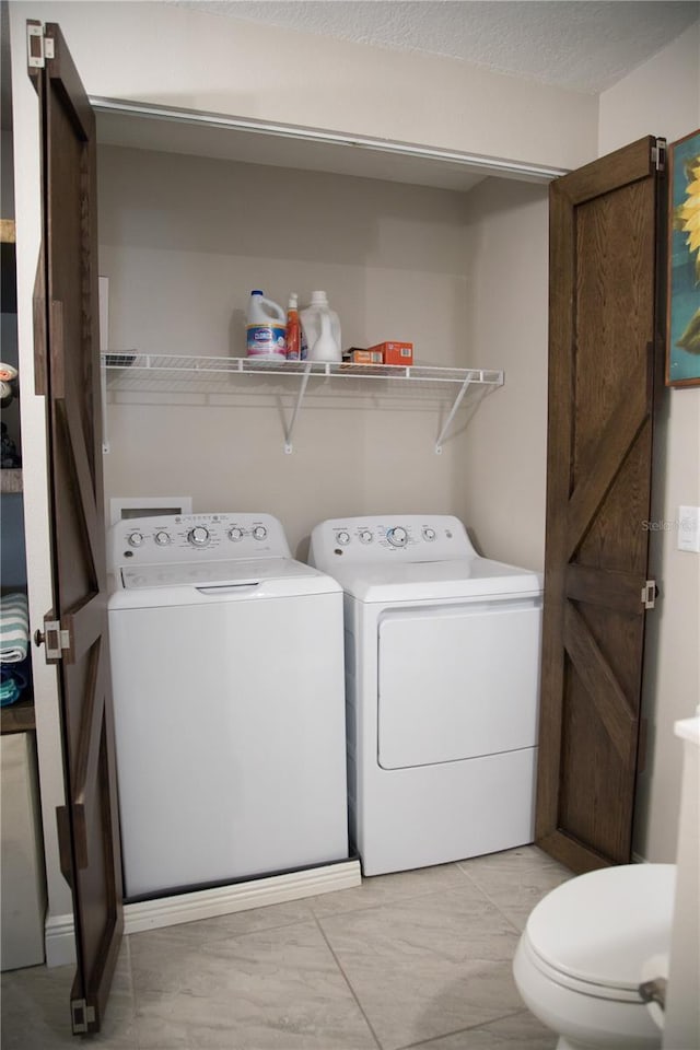 laundry room with a textured ceiling and washing machine and clothes dryer