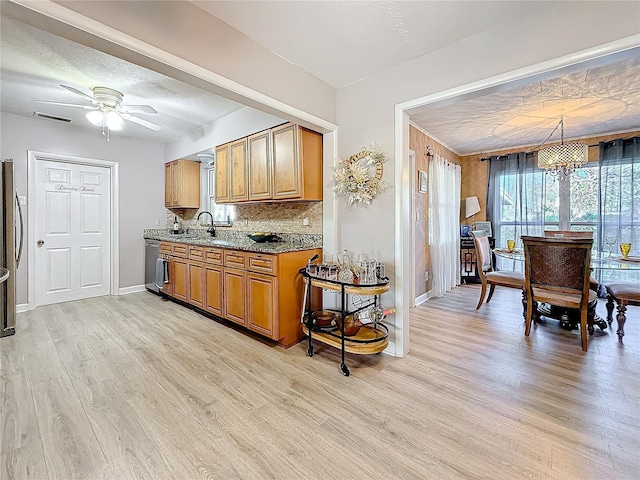 4100 Narvarez Way S, Saint Petersburg, FL 33712 - kitchen featuring brown cabinetry, light wood finished floors, a ceiling fan, a sink, and dark stone countertops