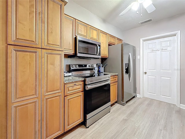 4100 Narvarez Way S, Saint Petersburg, FL 33712 - kitchen with stainless steel appliances, light wood-style floors, a ceiling fan, and brown cabinetry