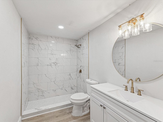 bathroom with toilet, wood finished floors, vanity, and a shower stall