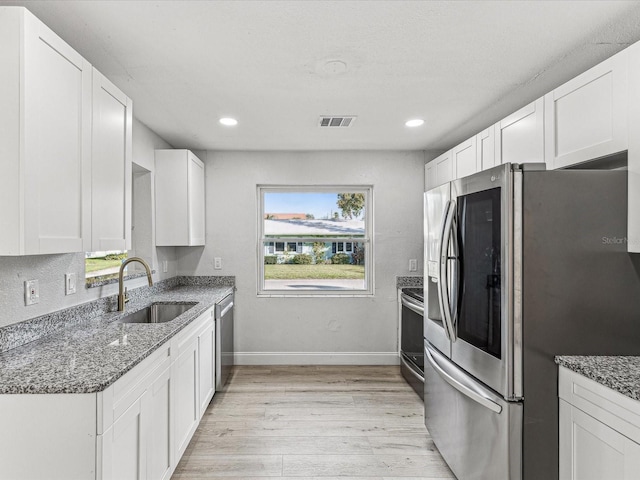 kitchen featuring light wood finished floors, white cabinetry, appliances with stainless steel finishes, and a sink