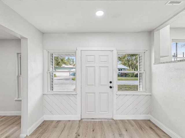 foyer featuring baseboards, visible vents, and light wood finished floors