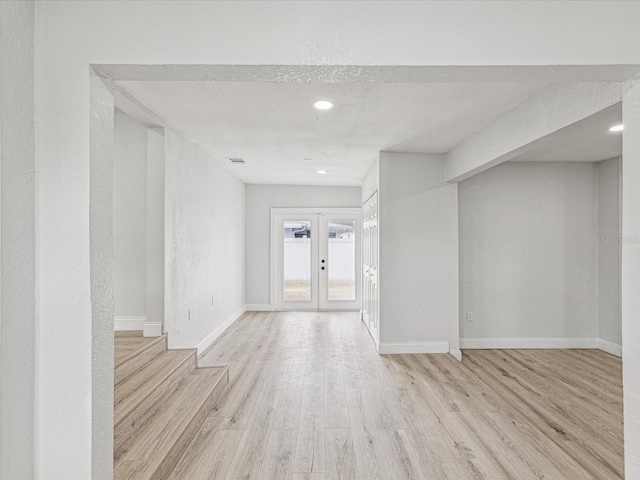 empty room featuring french doors, light wood-type flooring, recessed lighting, and baseboards