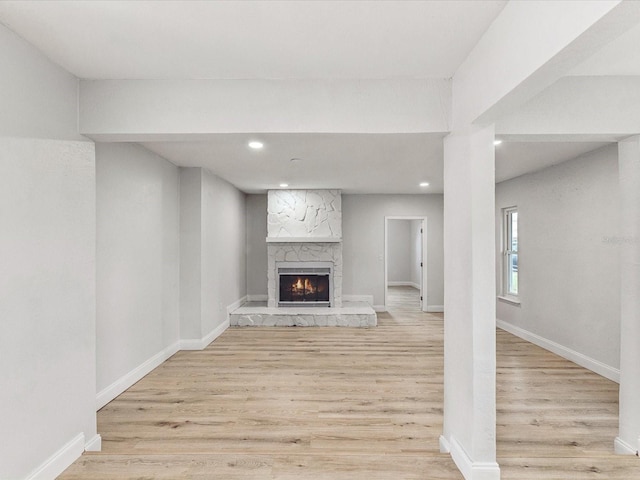 unfurnished living room with light wood-type flooring, a fireplace, baseboards, and recessed lighting