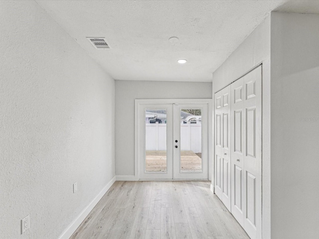 doorway to outside featuring a textured ceiling, visible vents, baseboards, french doors, and light wood-type flooring