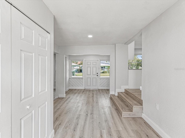 entryway featuring light wood-type flooring, stairs, and baseboards