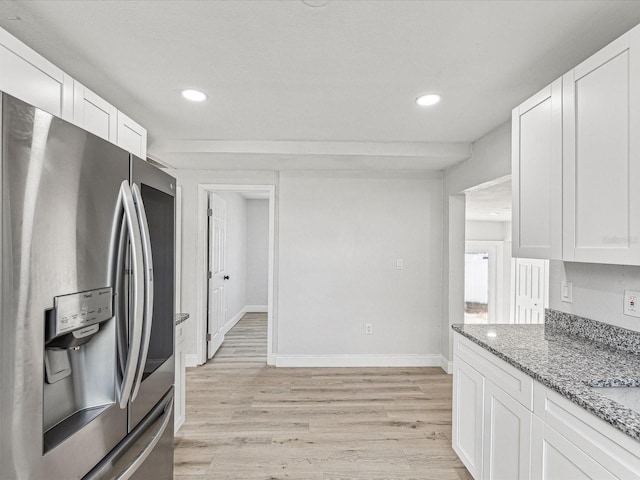 kitchen with light wood finished floors, light stone countertops, white cabinets, and stainless steel fridge with ice dispenser