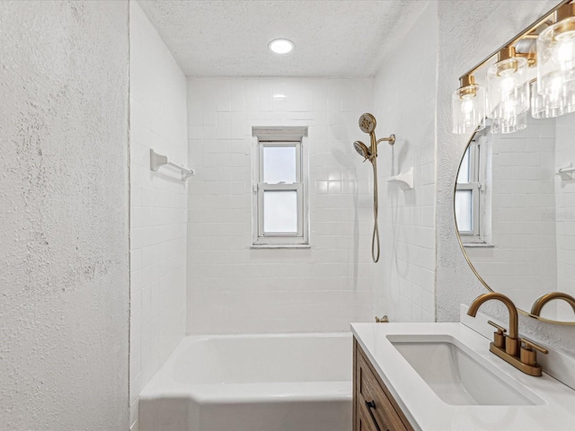 full bathroom featuring vanity, bathtub / shower combination, a textured ceiling, and a textured wall