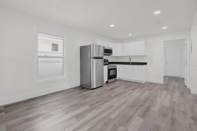 kitchen featuring baseboards, stainless steel appliances, light wood finished floors, and white cabinets