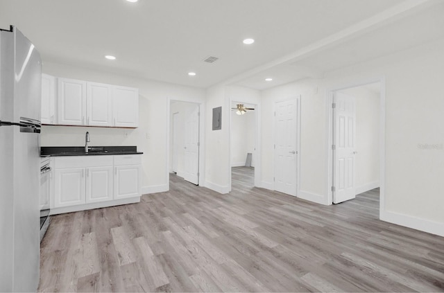 kitchen with freestanding refrigerator, dark countertops, a sink, and white cabinetry