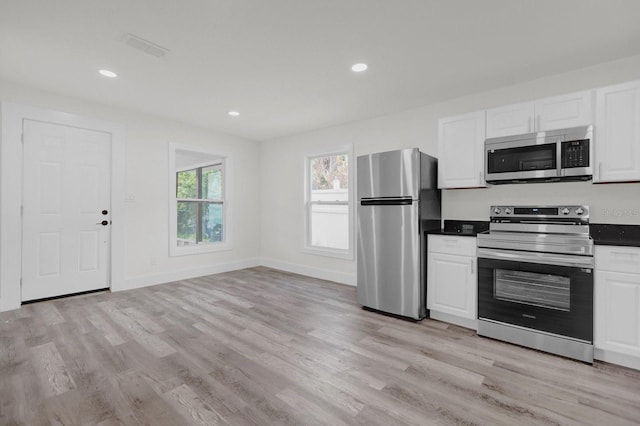 kitchen featuring stainless steel appliances, baseboards, white cabinets, light wood-type flooring, and dark countertops