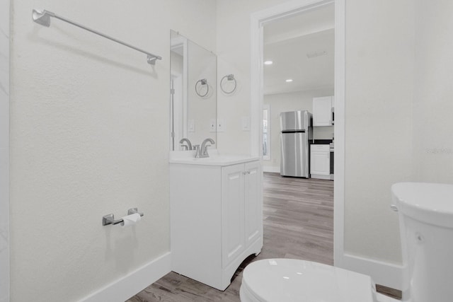 bathroom with wood finished floors, vanity, toilet, and baseboards