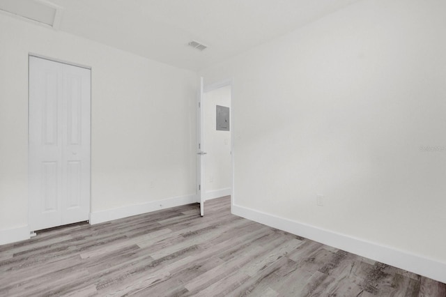 unfurnished room with light wood-style floors, baseboards, electric panel, and visible vents