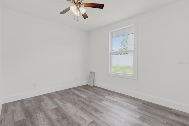 spare room featuring a ceiling fan, light wood finished floors, and baseboards