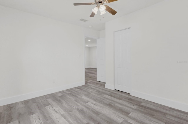 spare room featuring ceiling fan, light wood-style flooring, visible vents, and baseboards