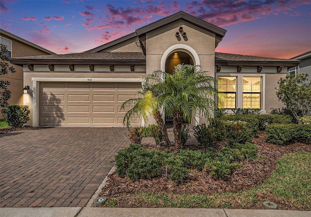 view of front of property with a garage, decorative driveway, and stucco siding