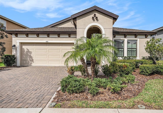 view of front of home featuring a garage, decorative driveway, roof with shingles, and stucco siding