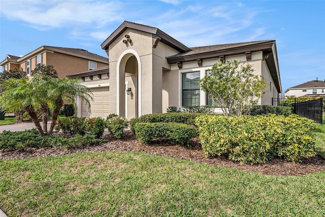 mediterranean / spanish-style house with a front yard, fence, an attached garage, and stucco siding