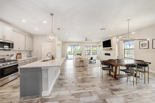 kitchen with white cabinets, an island with sink, appliances with stainless steel finishes, open floor plan, and a sink