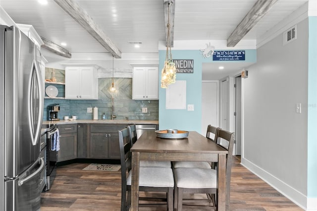 kitchen with visible vents, dark wood finished floors, decorative backsplash, beamed ceiling, and stainless steel appliances