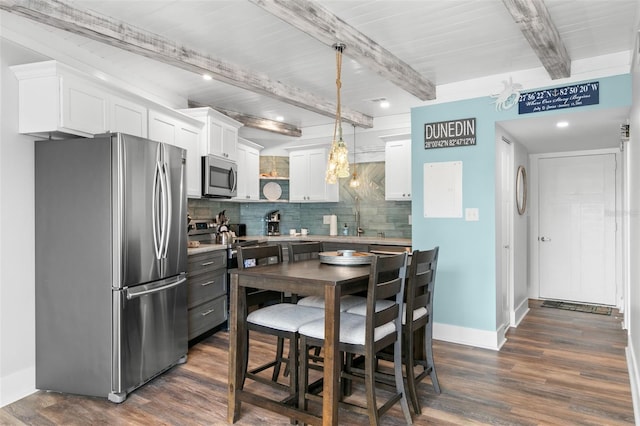 kitchen featuring tasteful backsplash, dark wood finished floors, white cabinets, appliances with stainless steel finishes, and beam ceiling