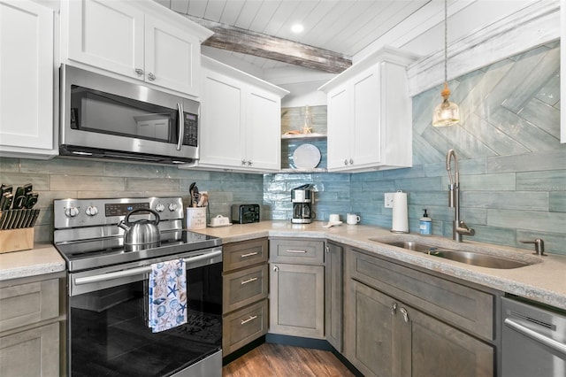 kitchen with decorative backsplash, wood finished floors, a sink, stainless steel appliances, and beam ceiling