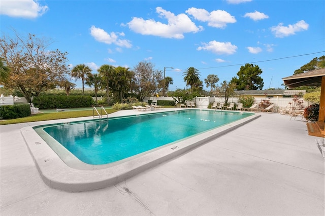 community pool with a patio area and a fenced backyard