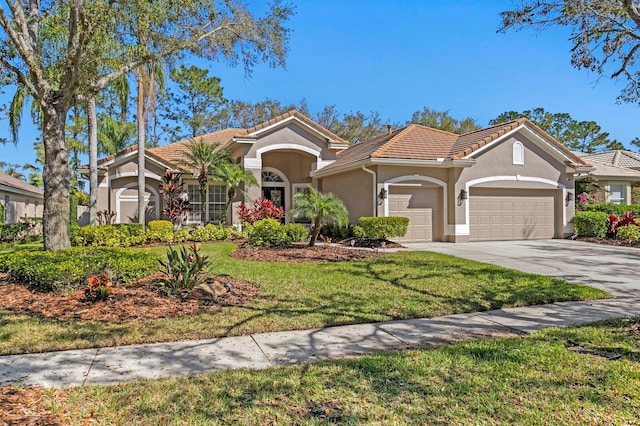 mediterranean / spanish-style home with a tile roof, stucco siding, an attached garage, driveway, and a front lawn