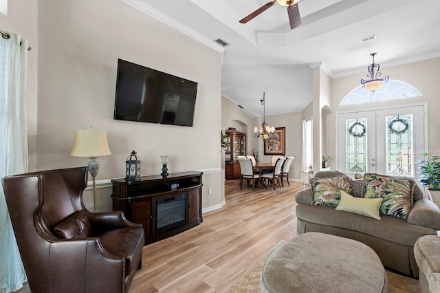 living area with light wood-style flooring, ceiling fan with notable chandelier, visible vents, baseboards, and ornamental molding