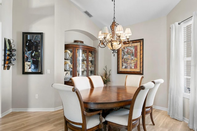 dining room with lofted ceiling, visible vents, baseboards, light wood-type flooring, and an inviting chandelier