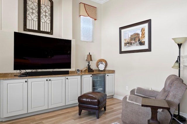 sitting room with light wood finished floors, wine cooler, and baseboards