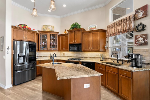 kitchen featuring black appliances, ornamental molding, a sink, and brown cabinets