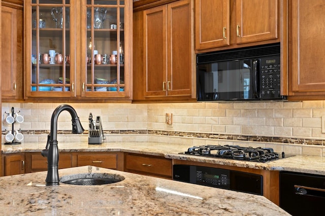 kitchen featuring brown cabinets, a sink, and black appliances