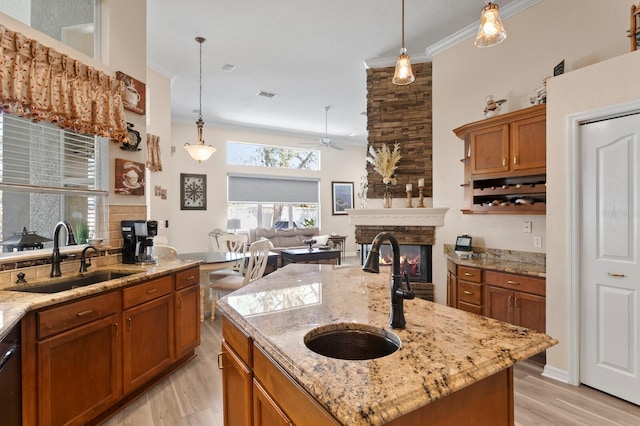 kitchen featuring crown molding, a fireplace, brown cabinets, and a sink