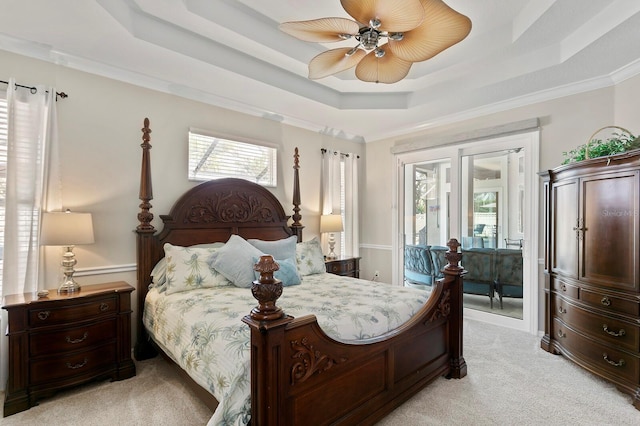 bedroom featuring light carpet, access to outside, multiple windows, and a raised ceiling