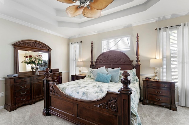 bedroom with ceiling fan, a tray ceiling, crown molding, and light colored carpet