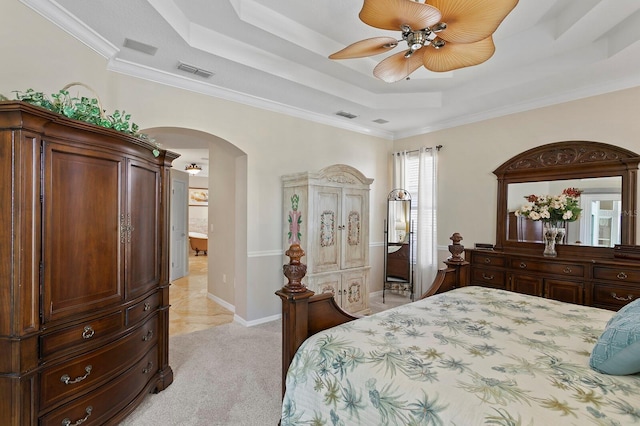 bedroom featuring arched walkways, a tray ceiling, light carpet, and visible vents