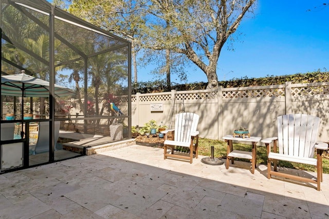 view of patio featuring fence and a lanai