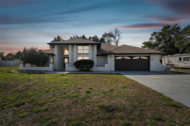 view of front of property featuring an attached garage, a front lawn, concrete driveway, and stucco siding