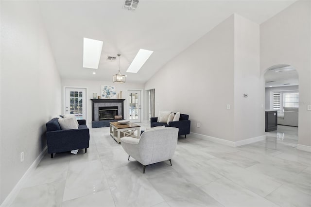 living area featuring a skylight, visible vents, high vaulted ceiling, and a high end fireplace