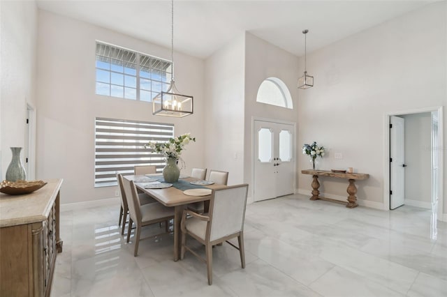 dining room with a notable chandelier, a towering ceiling, and baseboards