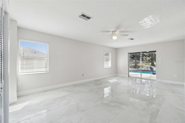 spare room featuring marble finish floor, a ceiling fan, visible vents, and baseboards