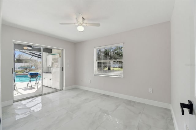 empty room featuring a sunroom, marble finish floor, and baseboards