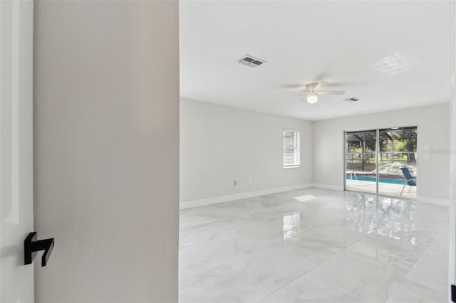 spare room featuring a sunroom, a ceiling fan, visible vents, marble finish floor, and baseboards