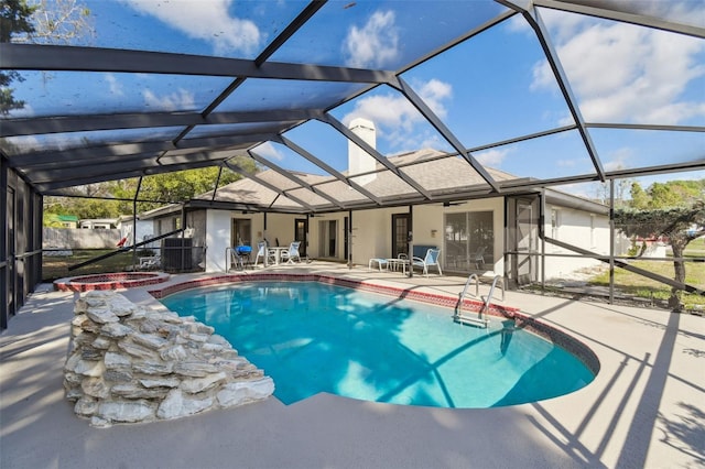 outdoor pool with a lanai, a patio area, and an in ground hot tub