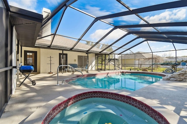 outdoor pool featuring glass enclosure, a patio area, and an in ground hot tub