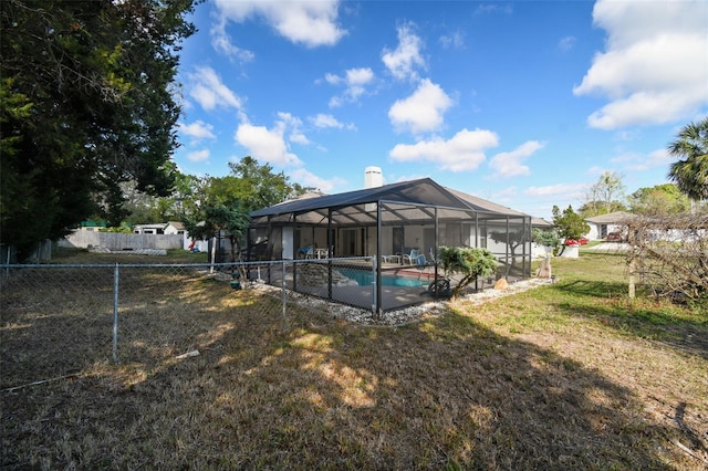 exterior space featuring glass enclosure, a lawn, fence private yard, and a fenced in pool