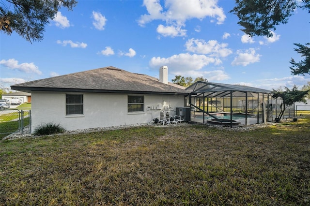 rear view of house with glass enclosure, an outdoor pool, a lawn, and stucco siding