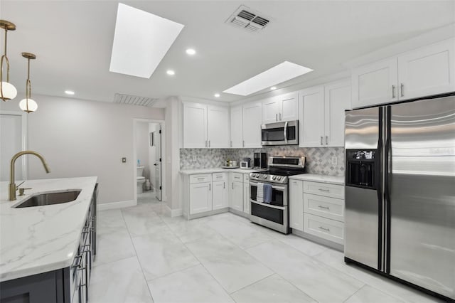 kitchen with pendant lighting, visible vents, appliances with stainless steel finishes, white cabinets, and a sink